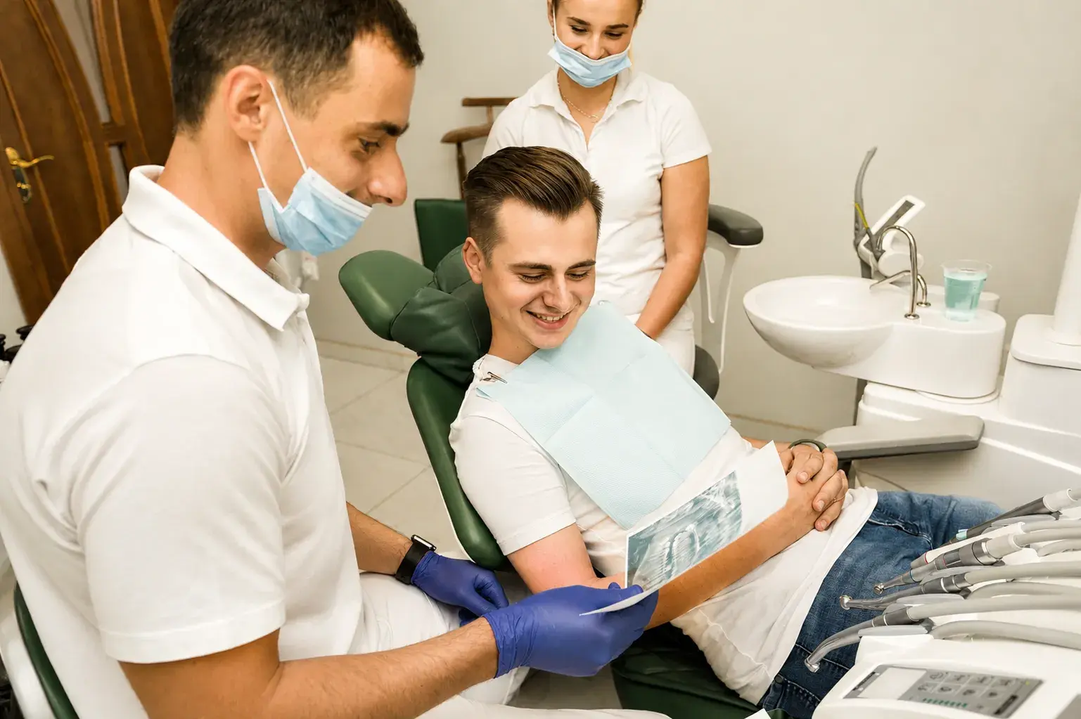 Dentist explaining an X-ray to a smiling patient in the treatment room