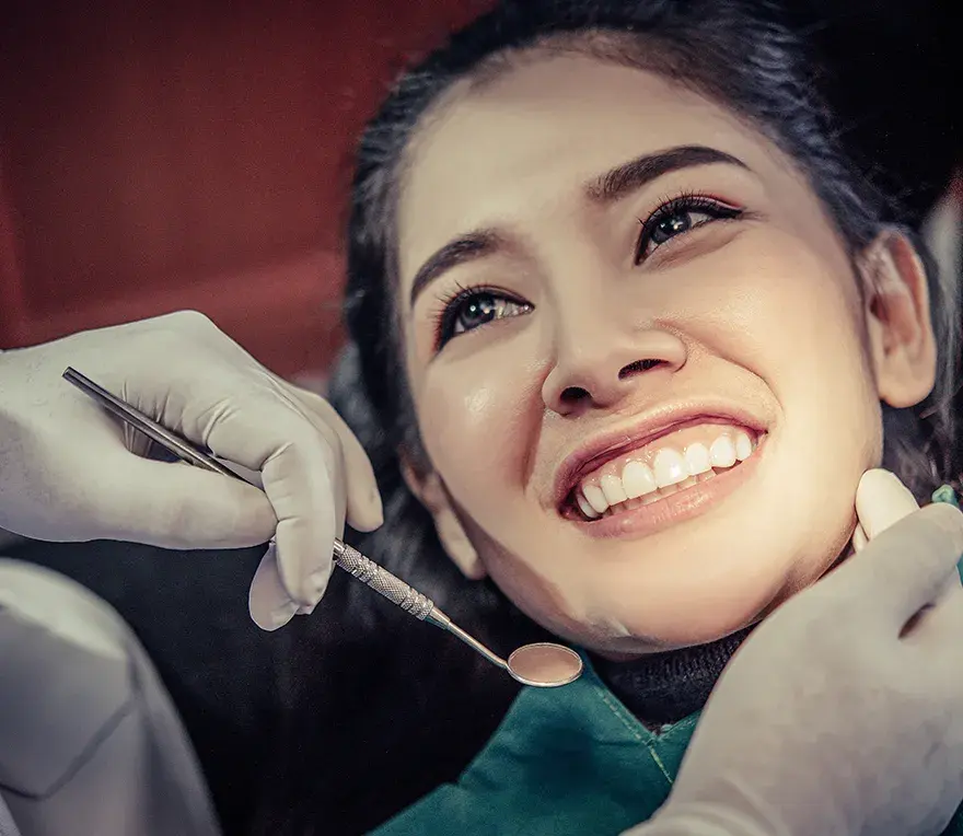 A smiling patient having their teeth examined with a dental mirror