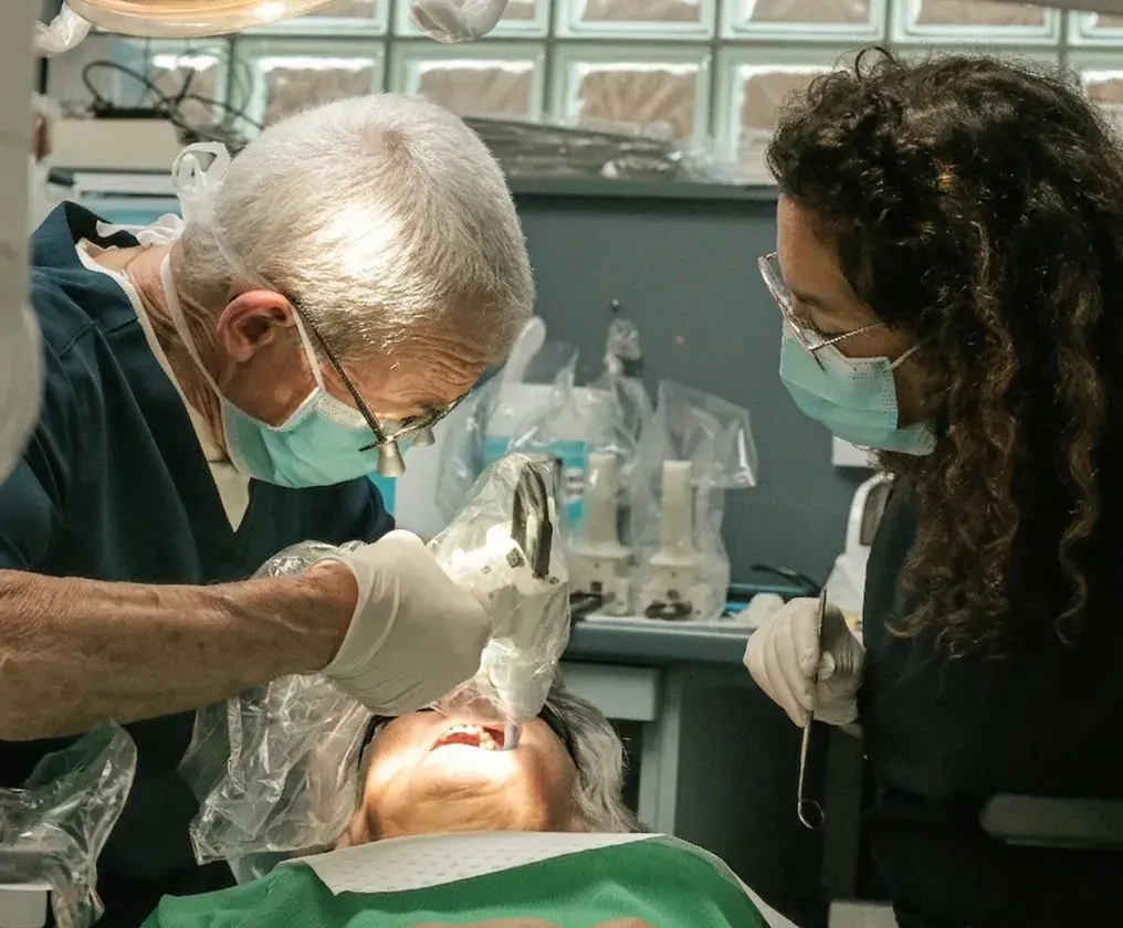 Two dentists placing a tooth-coloured filling for a patient in the treatment chair