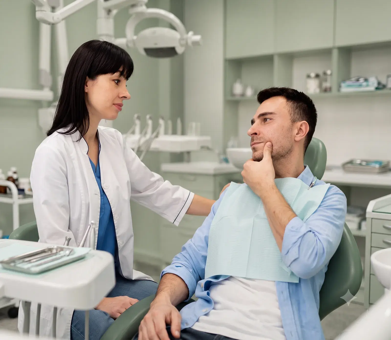 A dentist reassuringly speaking with a patient in the treatment chair before a procedure
