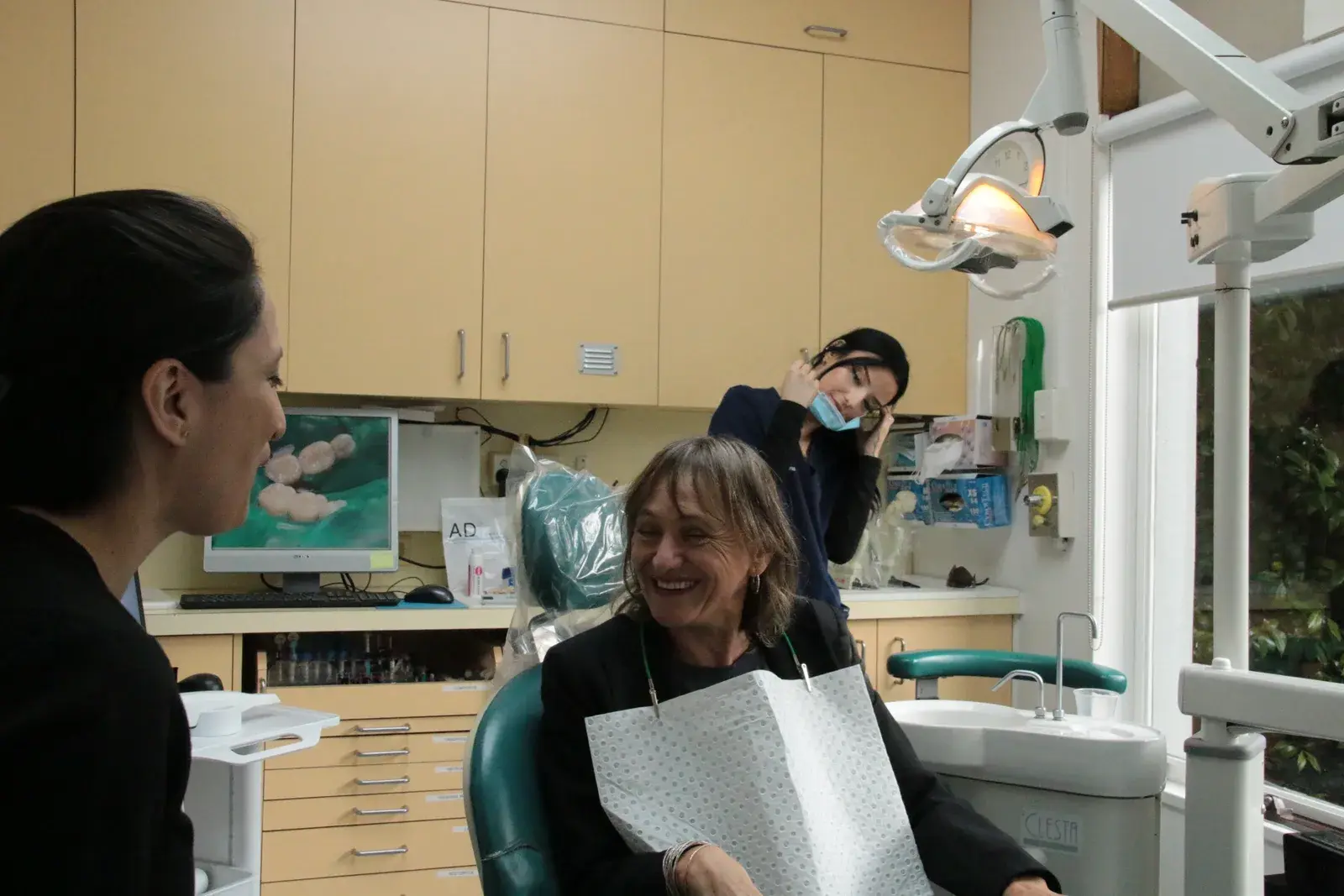 A dentist speaking with a smiling patient in the treatment room